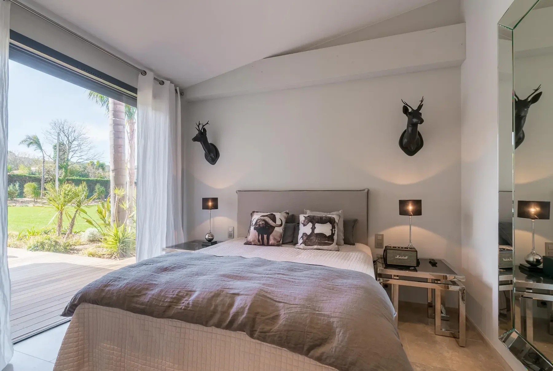 Cama doble con adornos colgados encima y una puerta corredera de cristal que da a la terraza