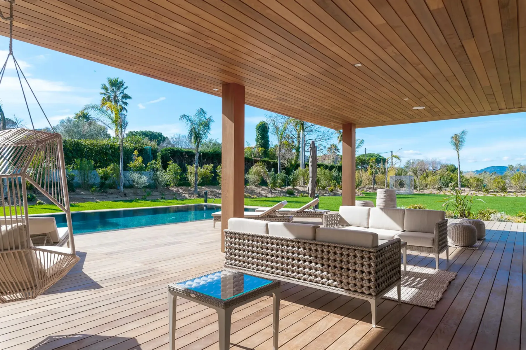 Muebles de exterior sobre una tarima revestida de madera con vistas a la piscina