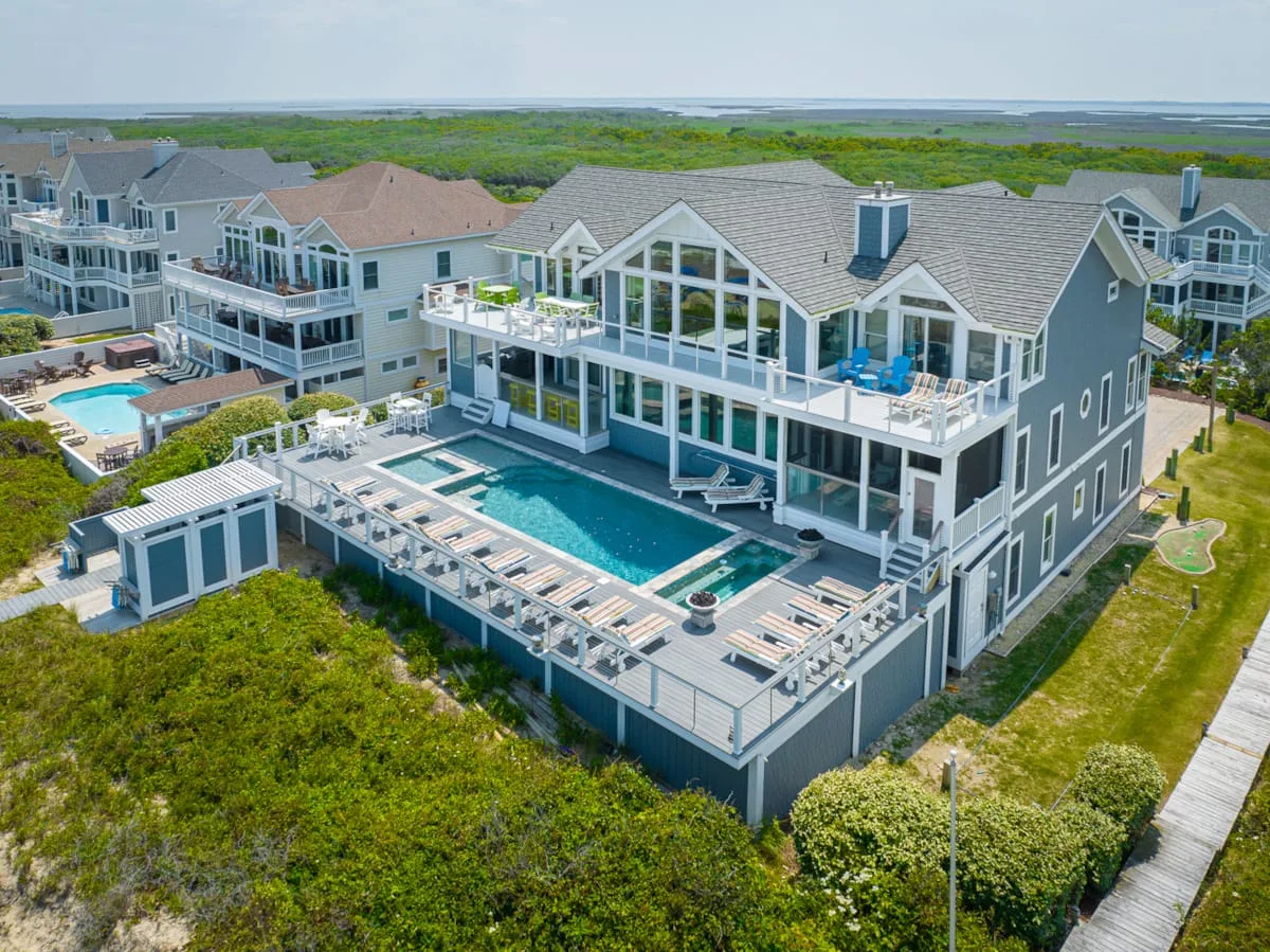 A large coastal house with a swimming pool and surrounding greenery.
