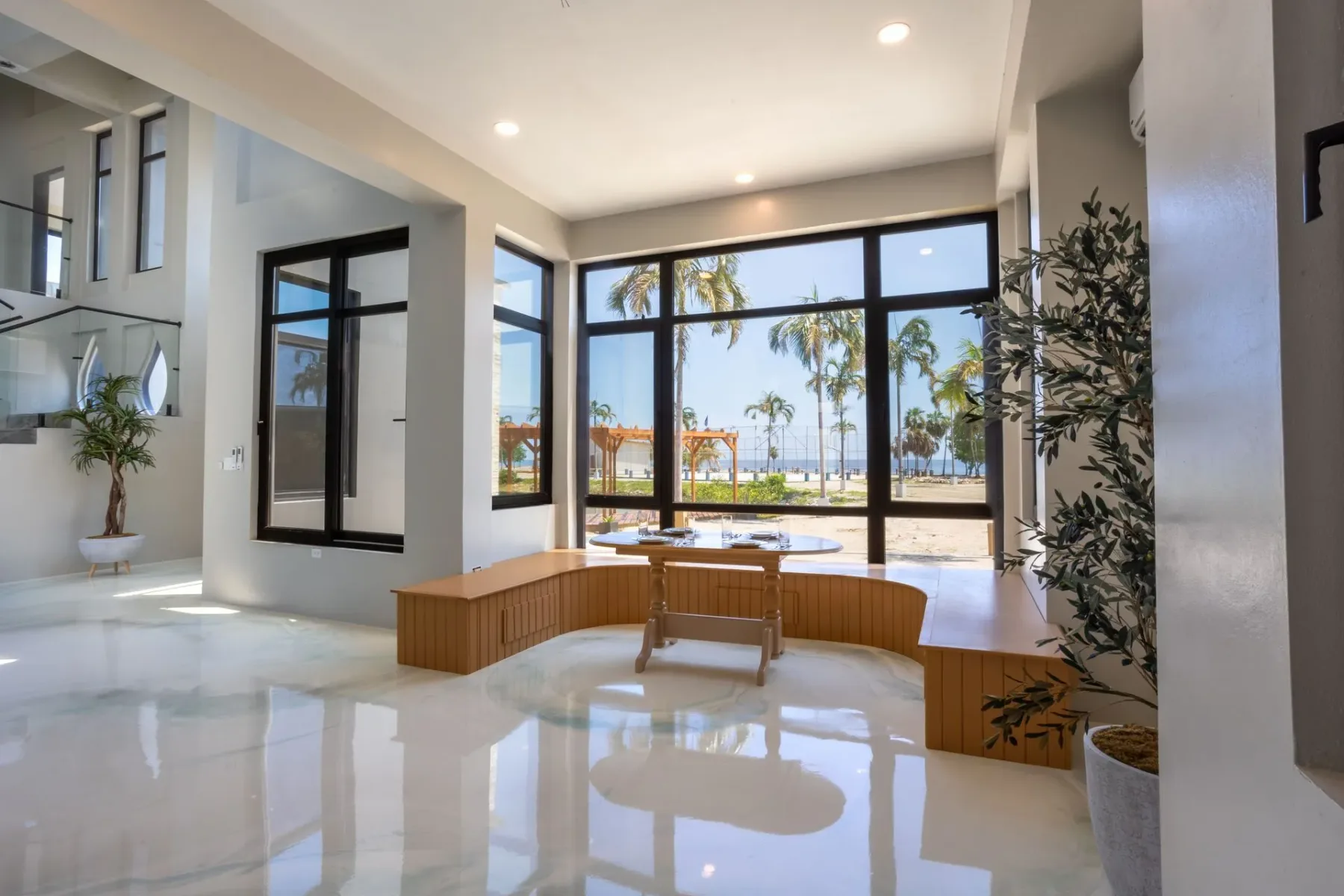 Living room with beige furniture and large windows overlooking trees and water.
