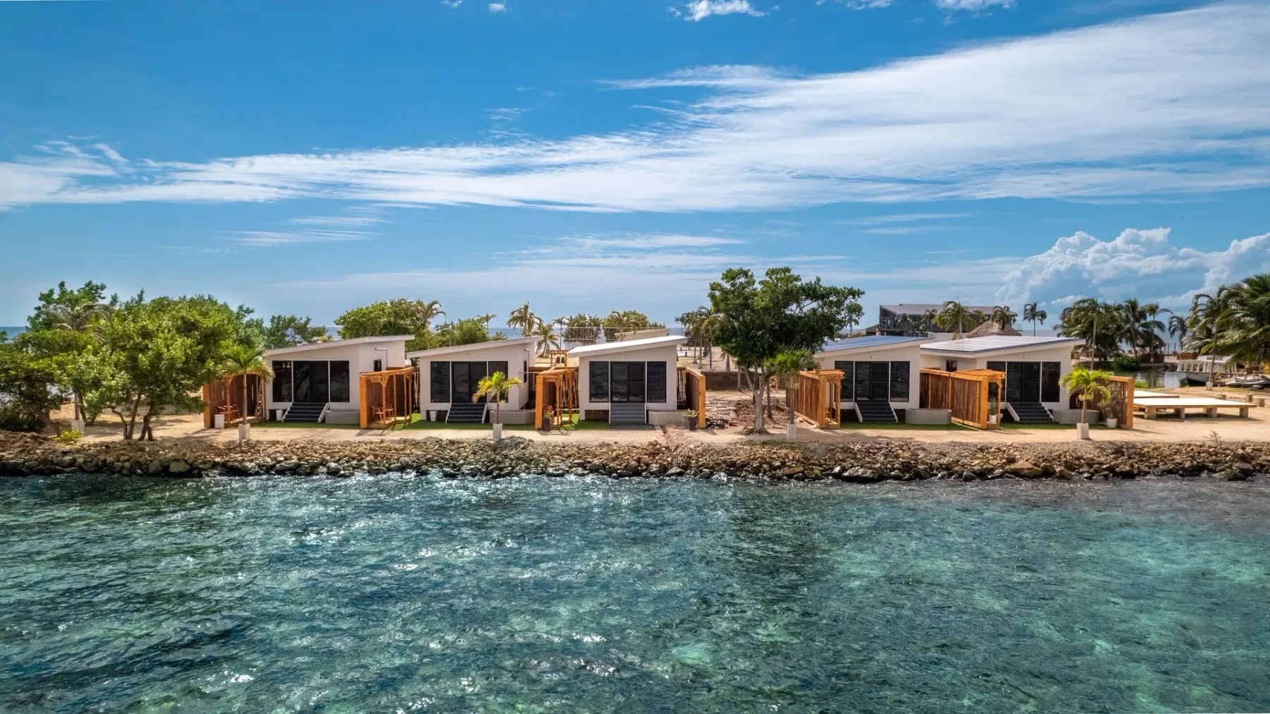 Beachfront villas beside clear blue water.
