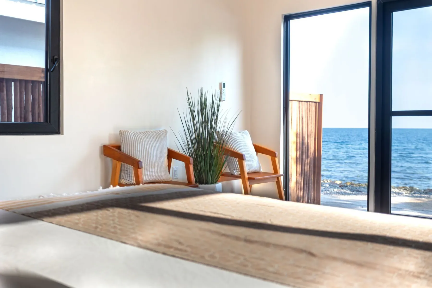 Bedroom with a chair and ocean views through open glass doors.