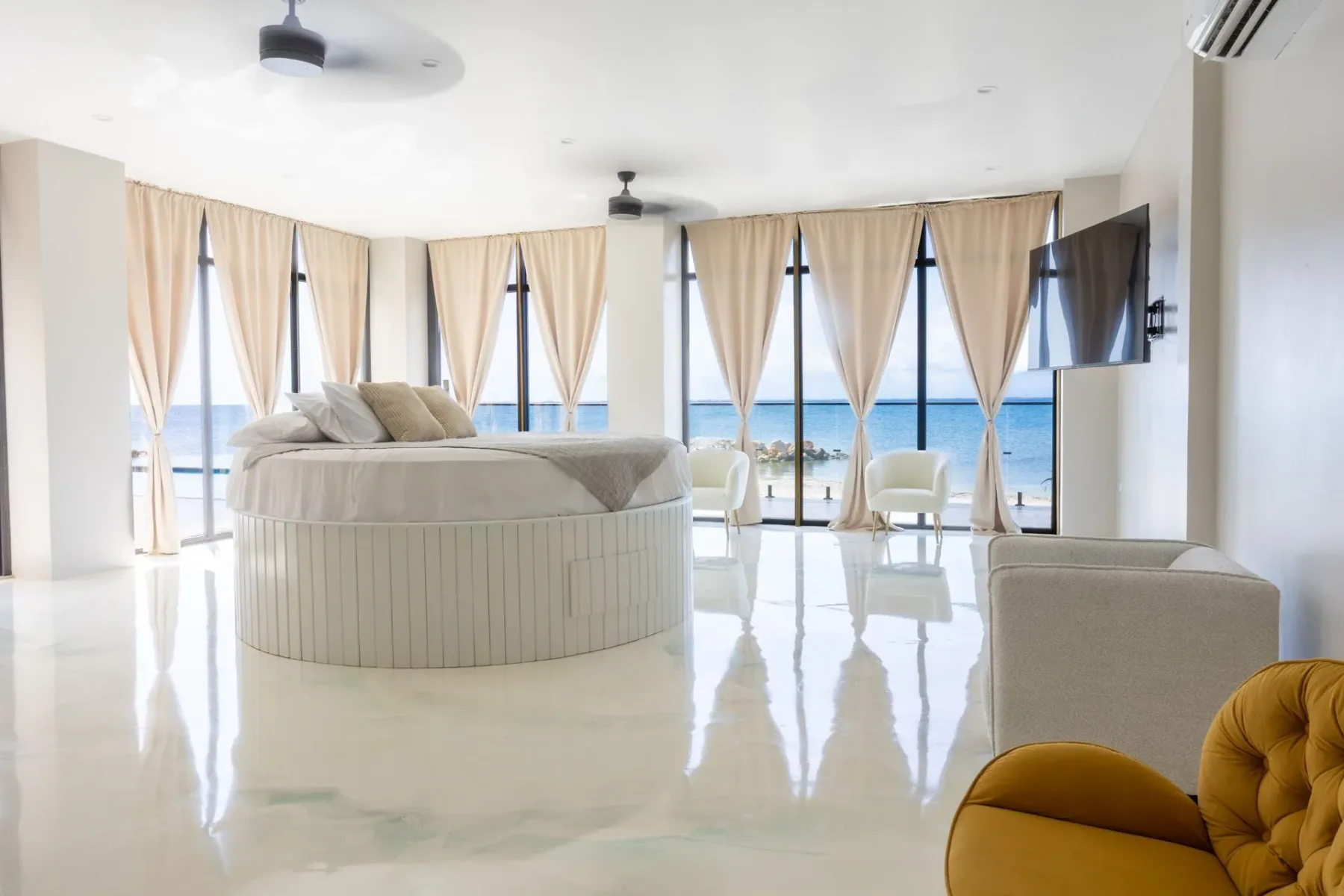 Bedroom with a round bed and ocean views through large windows.