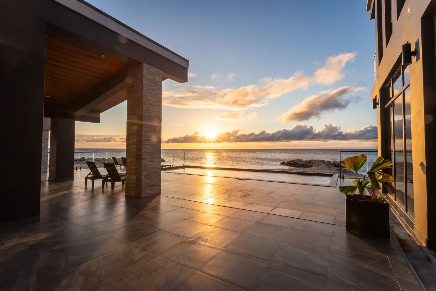 Seaside patio at sunset with ocean waves beyond.