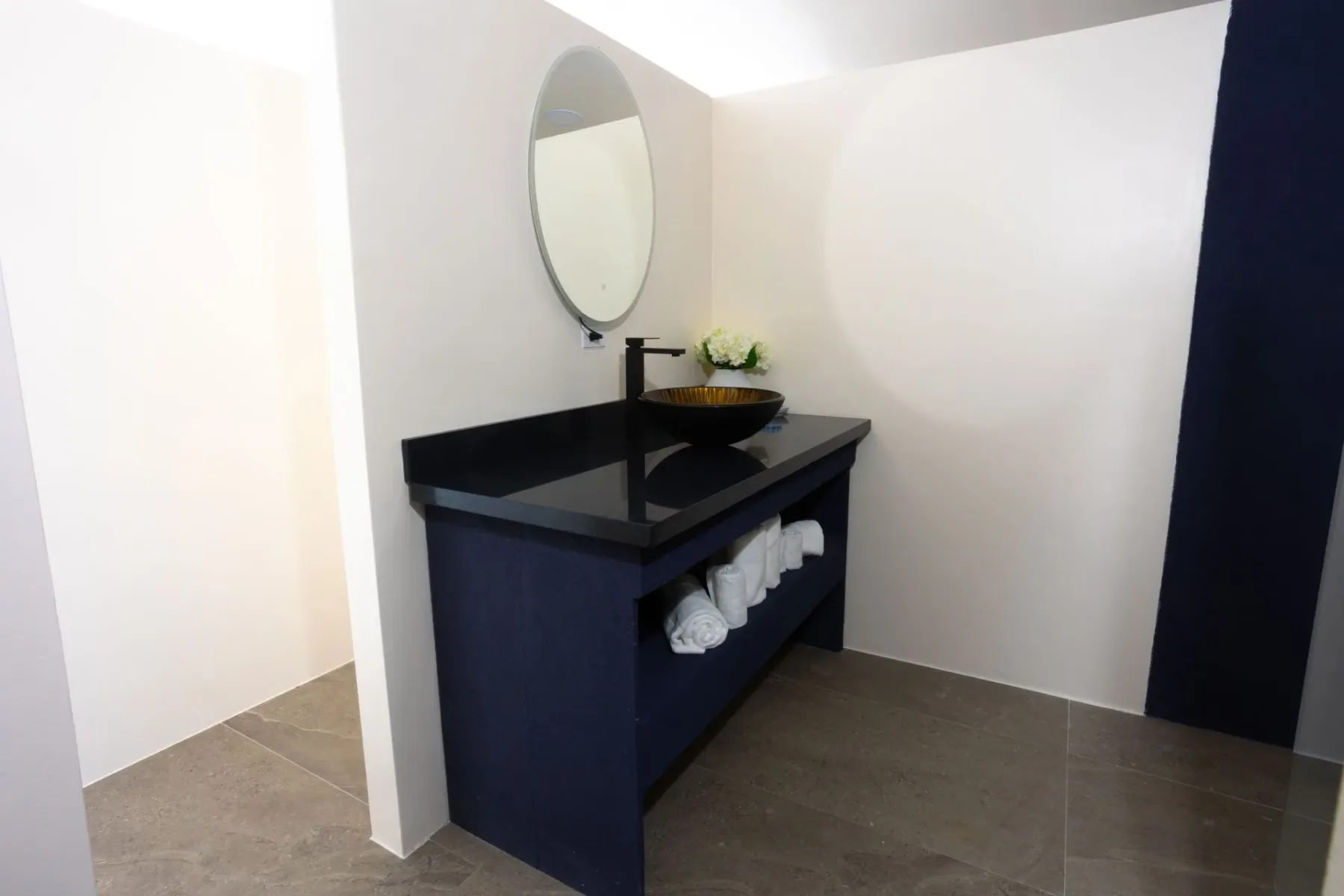 Bathroom vanity with a round mirror and dark cabinet.