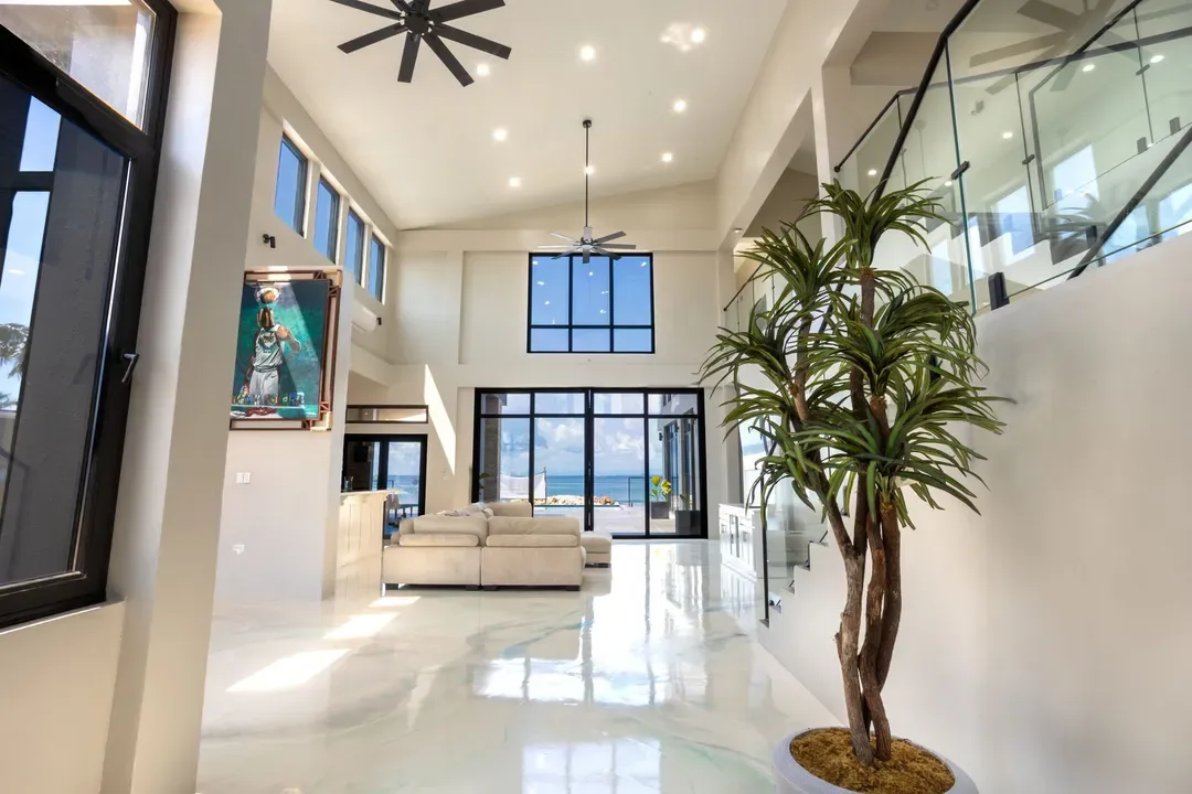 Bright living room with a white sofa, large windows, and an indoor plant.