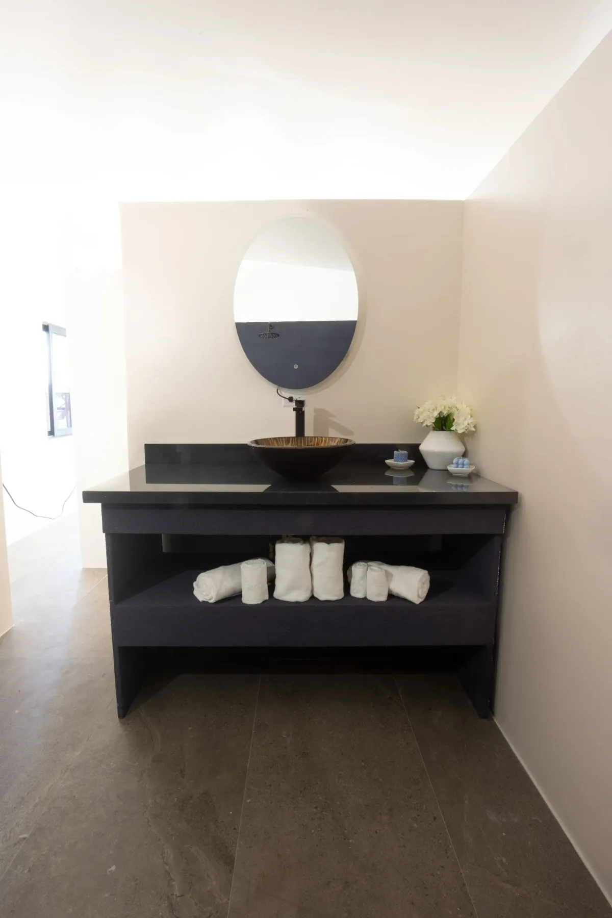 Bathroom vanity with an oval mirror and rolled towels.