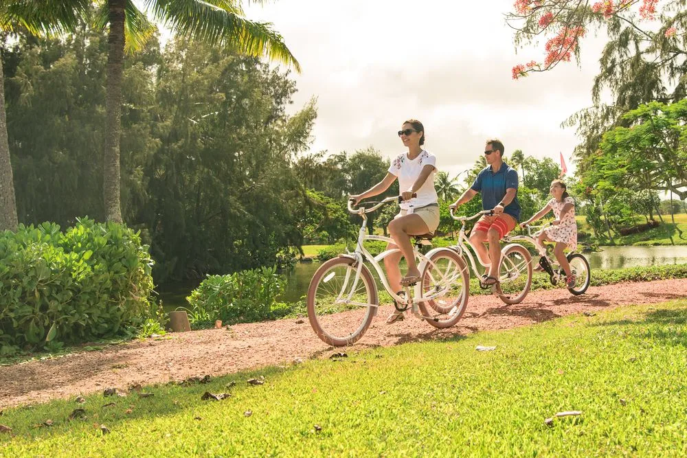 Varias personas montan en bicicleta por un sendero entre zonas verdes.