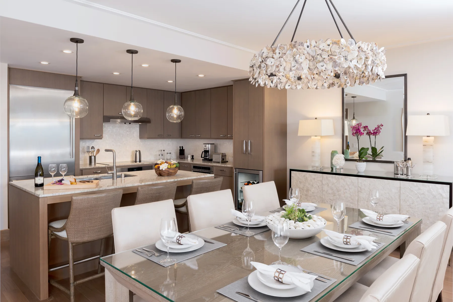 Comedor con una mesa de vidrio junto a una cocina abierta.