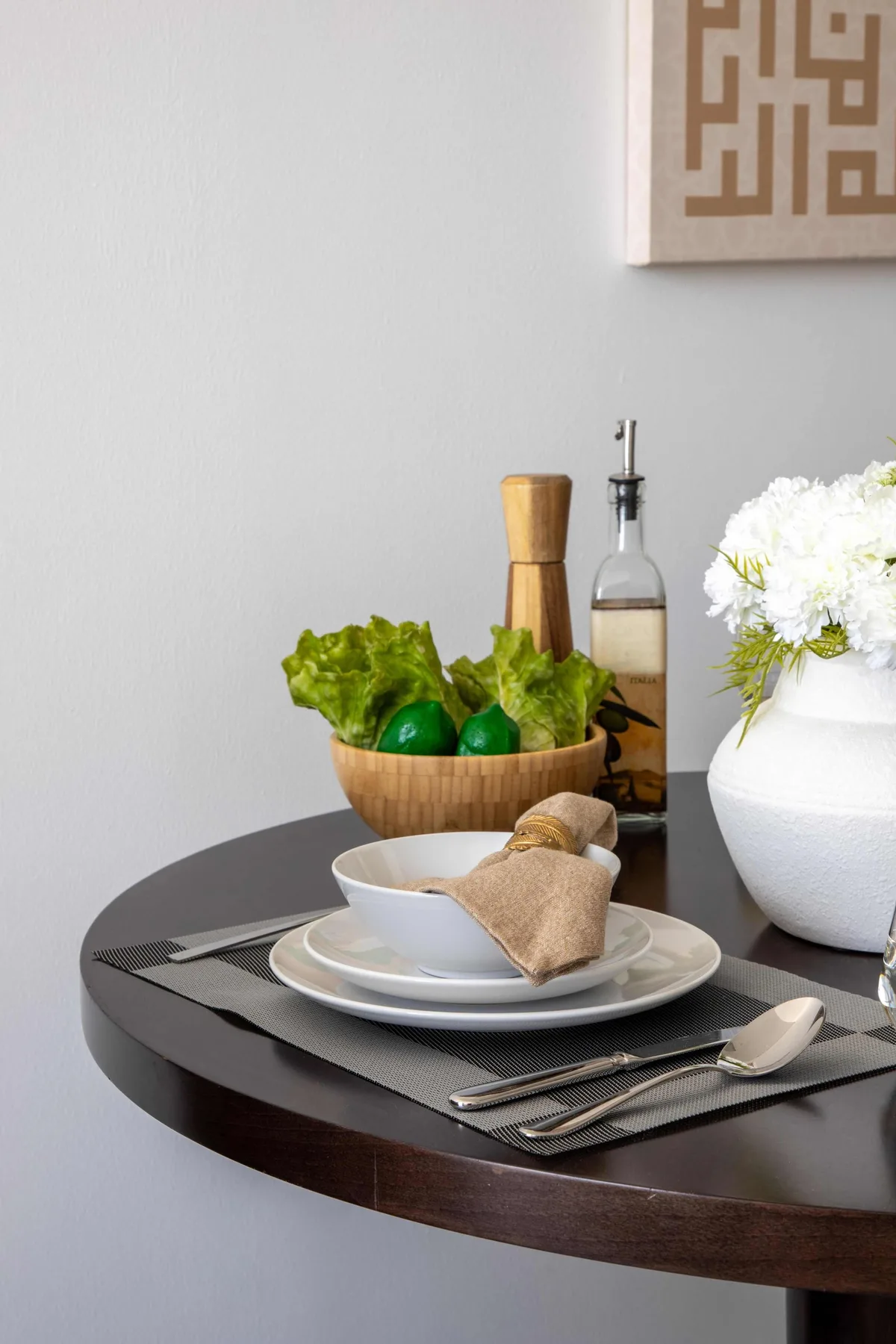 Una mesa de comedor está preparada con platos, cubiertos, verduras y flores.