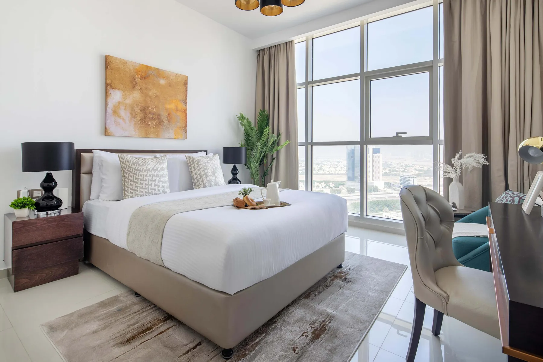 Un dormitorio luminoso con una cama grande junto a ventanas altas.