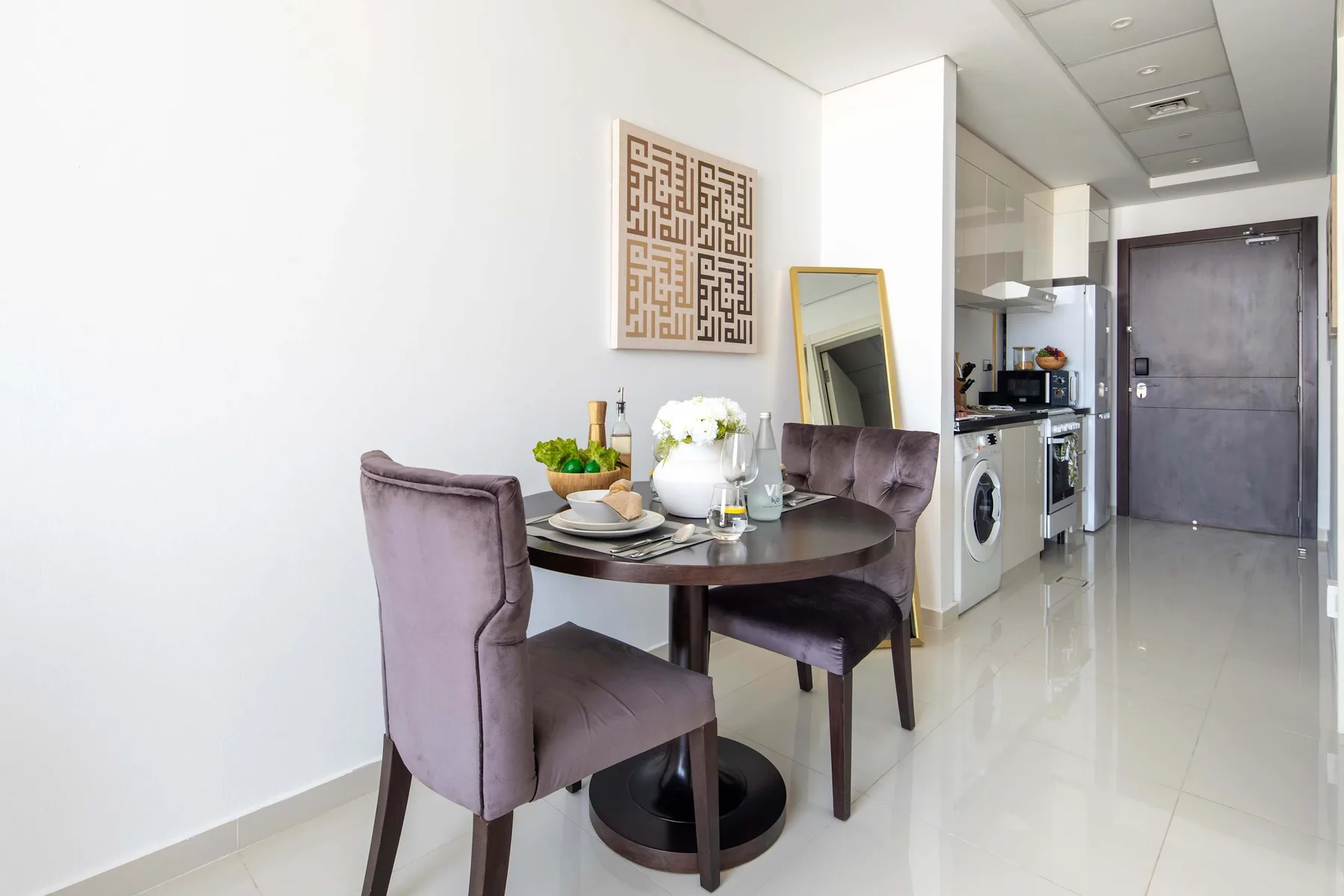 Comedor con una mesa redonda y asientos tapizados junto a una cocina compacta.