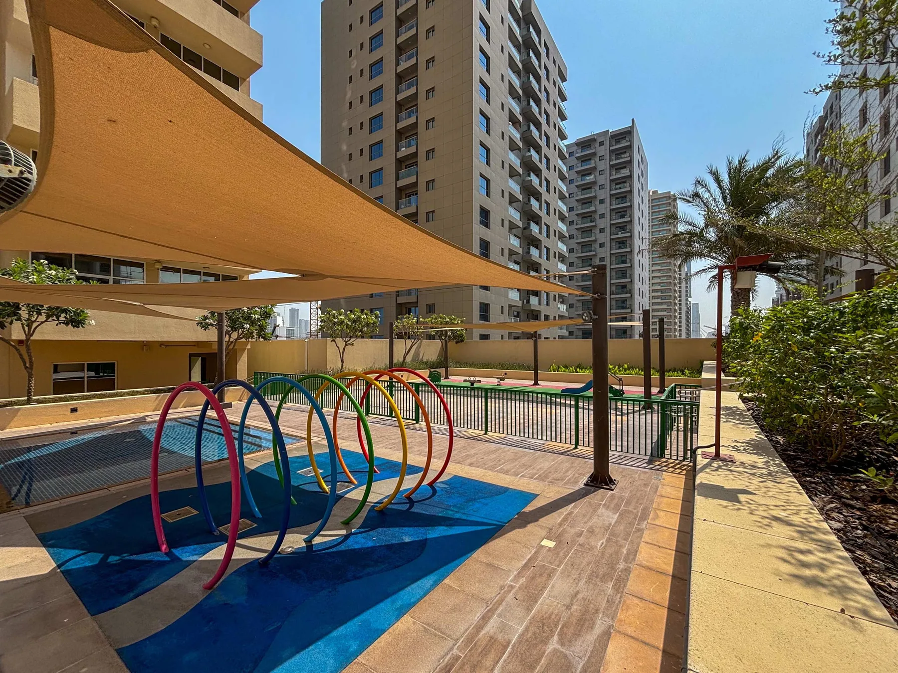 Una zona de piscina al aire libre, con estructuras curvas de colores y edificios altos.