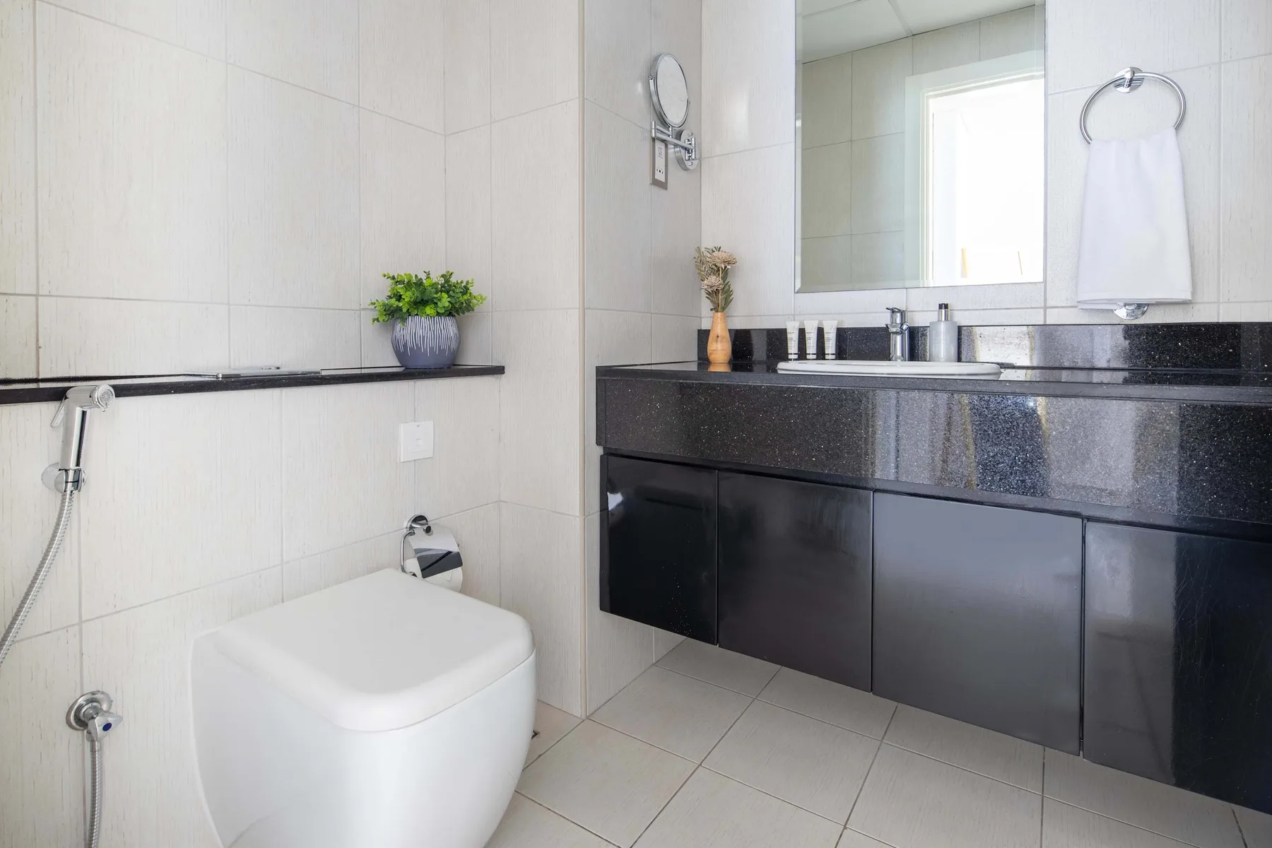 Un baño alicatado con inodoro, mueble oscuro y espejo.