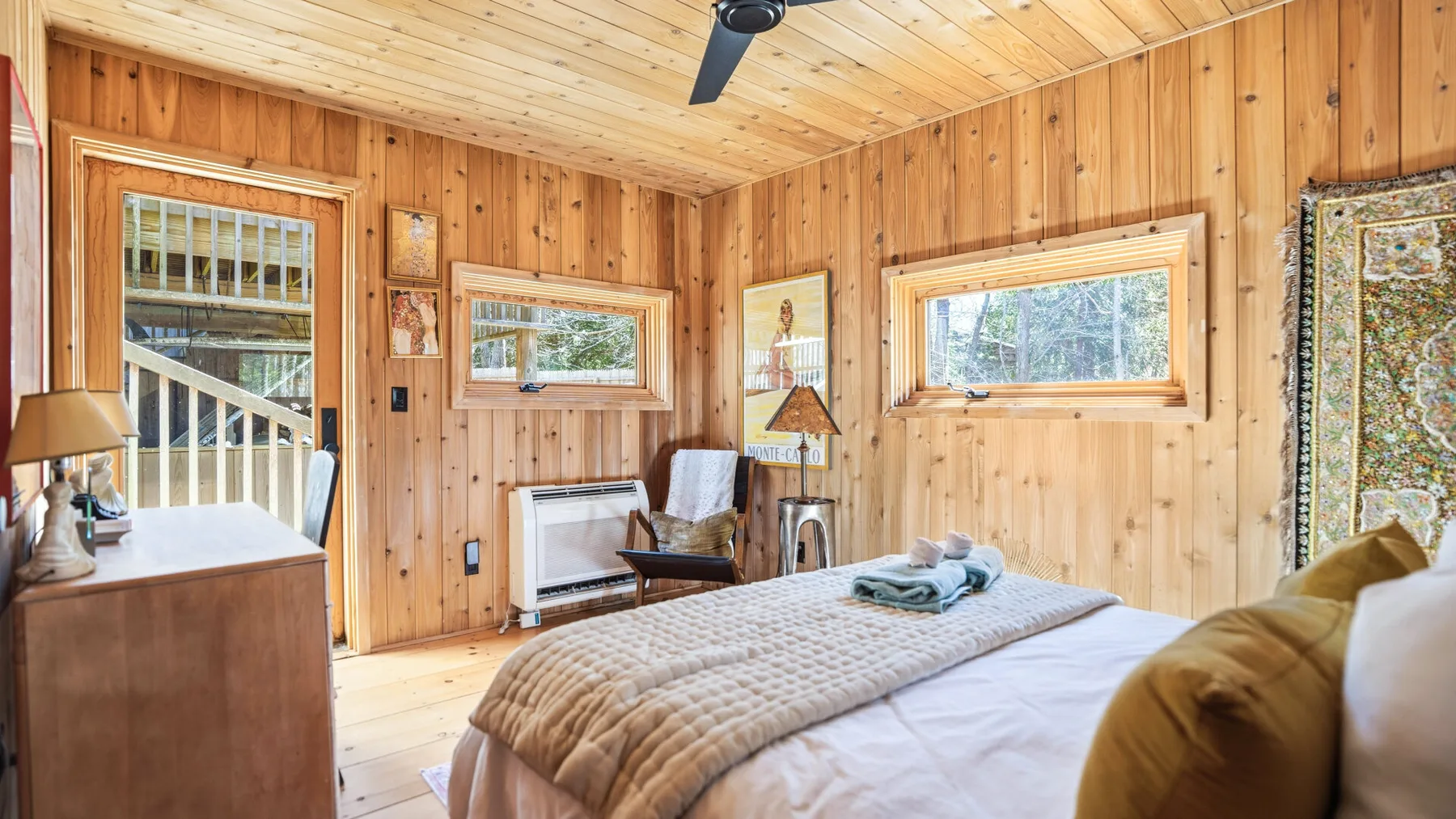 Un dormitorio revestido de madera con una cama y ventanas.