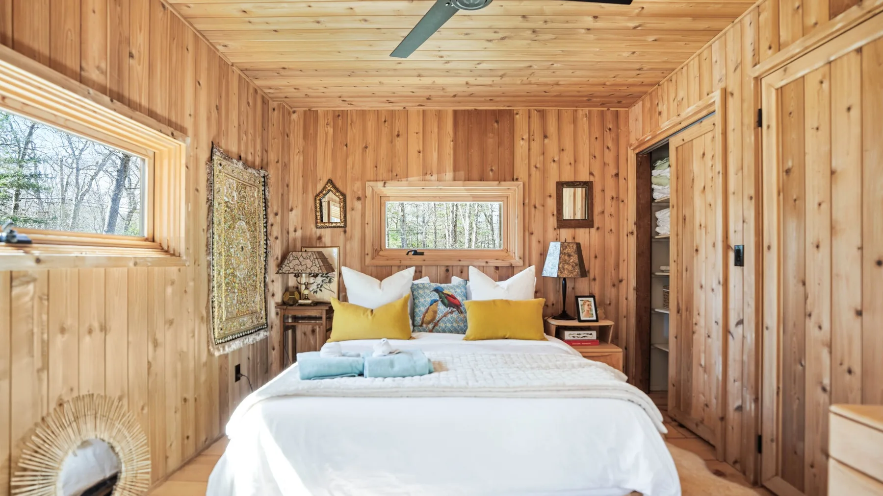 Un dormitorio revestido de madera con una cama bajo una ventana.