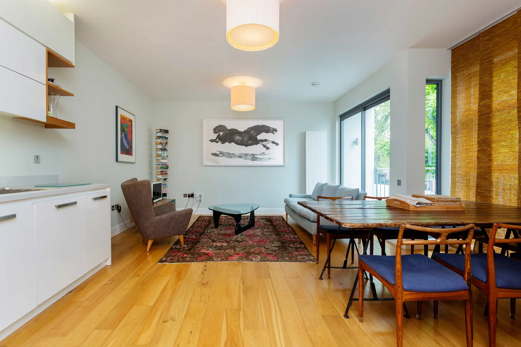 A bright open-plan living and dining area with seating around a low table.