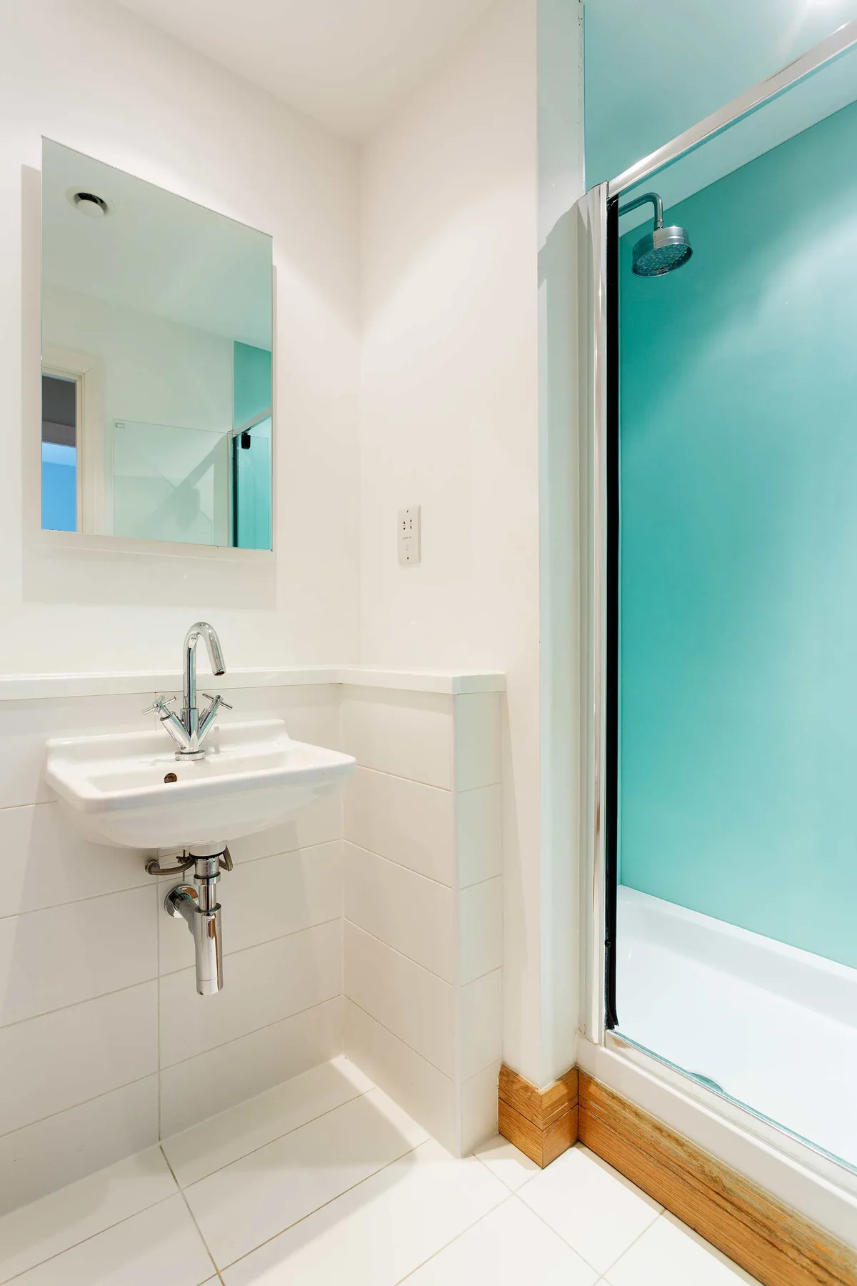 A bright bathroom with a wall-mounted sink and a glass-enclosed shower.
