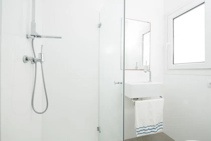 Un baño luminoso con ducha de vidrio, lavabo y ventana.