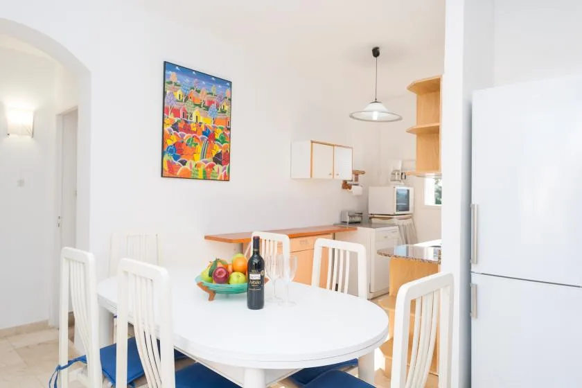 Una cocina y comedor luminosos con una mesa blanca y arte colorido en la pared.