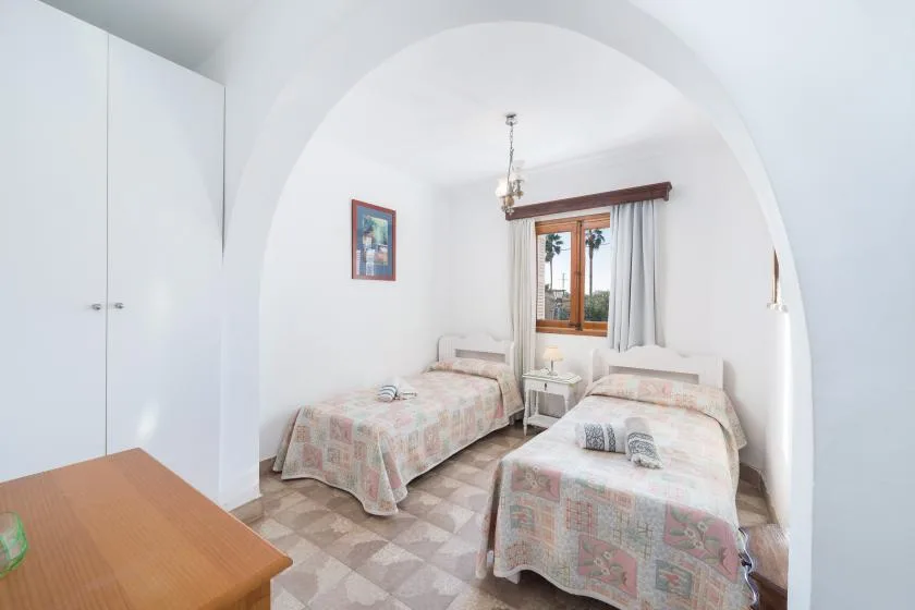 Un dormitorio luminoso con dos camas individuales y una ventana entre ellas.