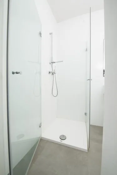 Un baño luminoso con una ducha de vidrio y accesorios de ducha en la pared.
