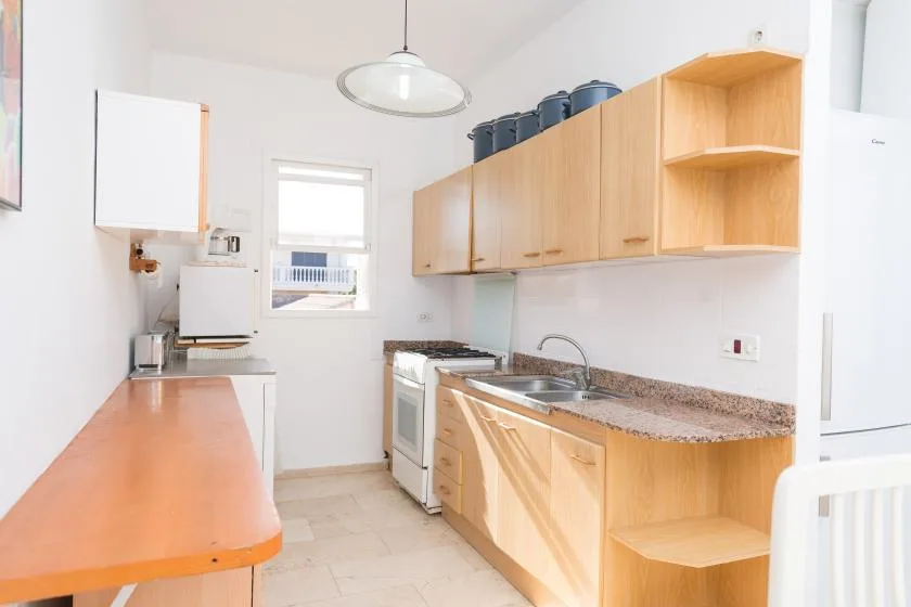 Una cocina luminosa con gabinetes de madera, una encimera y un fregadero.