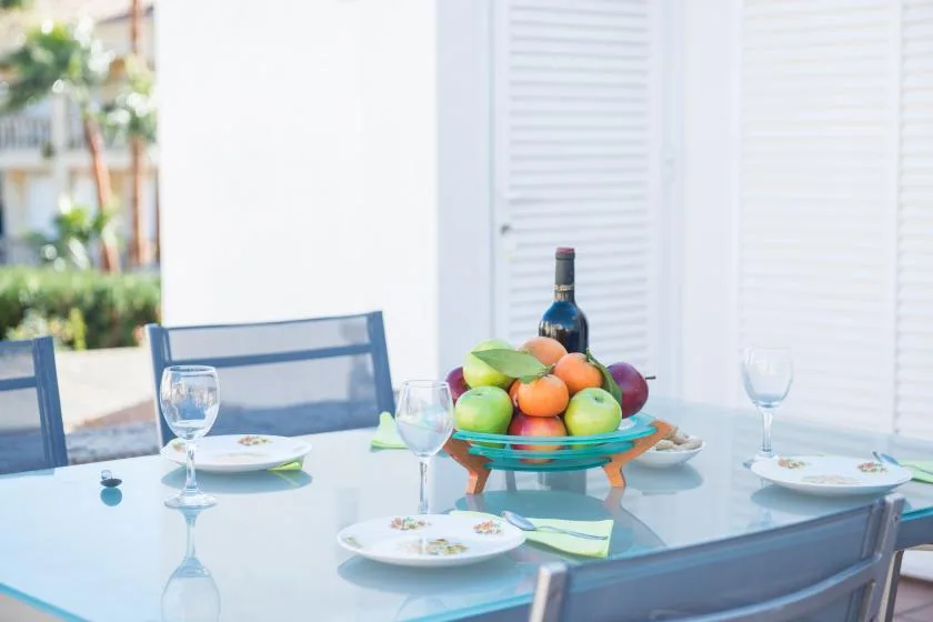Una mesa de comedor está puesta con platos, copas y un frutero.
