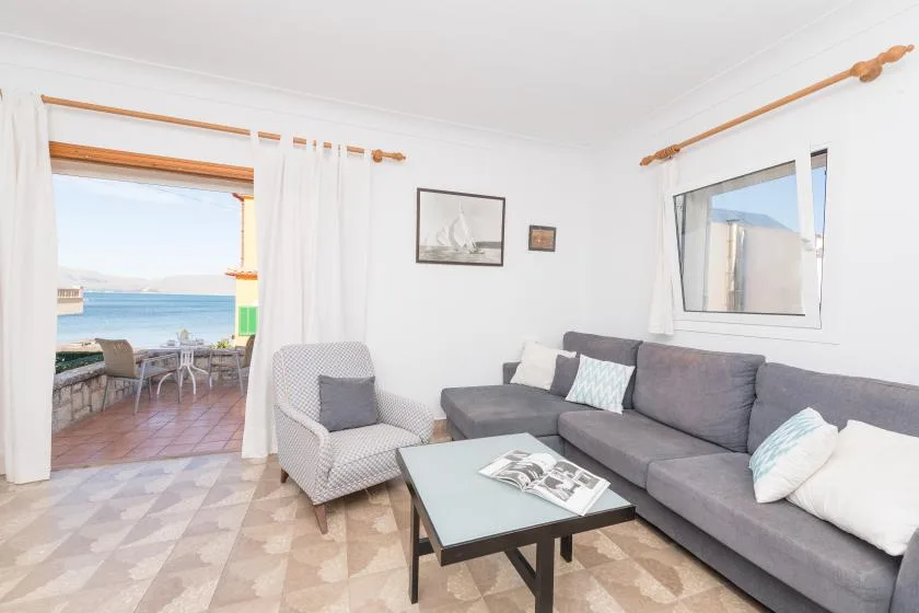 Una luminosa sala de estar con asientos seccionales y vista al mar por la puerta abierta.