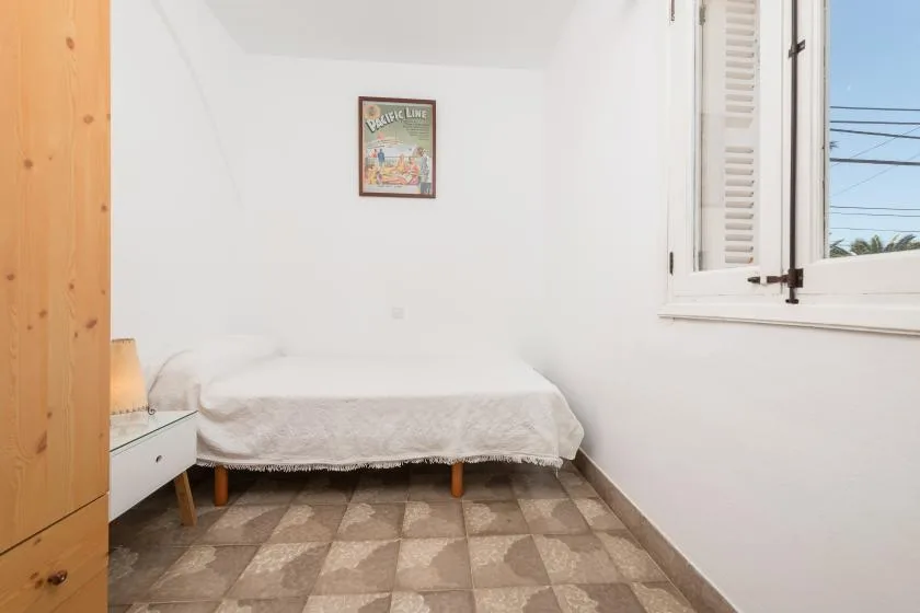 Un dormitorio sencillo con una cama debajo de un pequeño cuadro enmarcado.