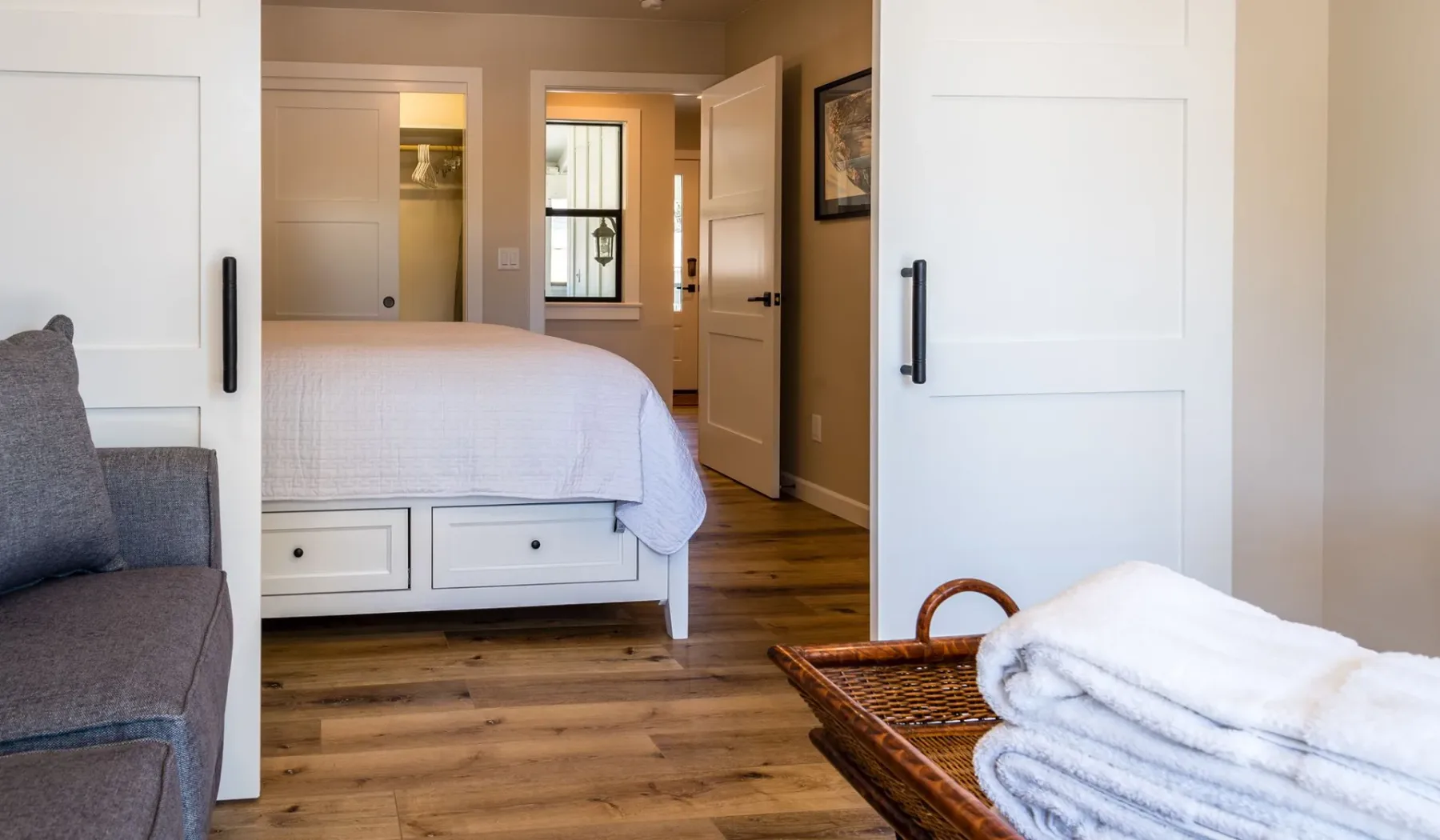 Un dormitorio con una cama bien arreglada y suelo de madera.