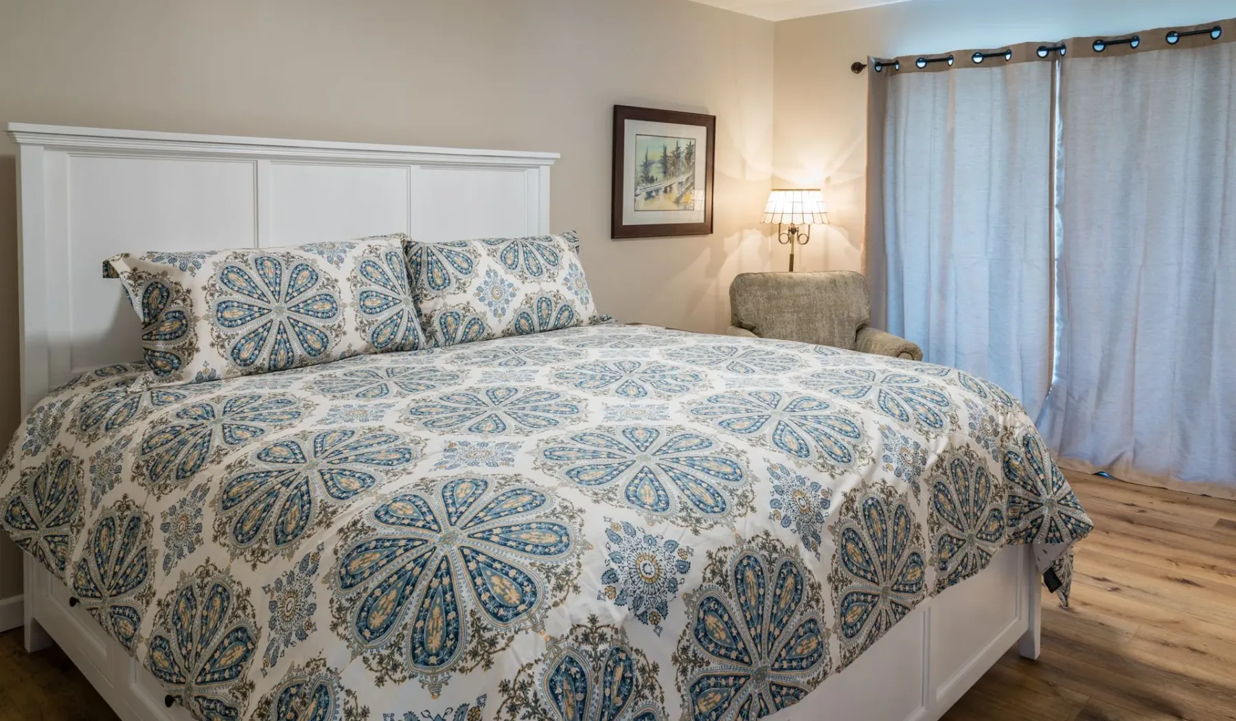 Un dormitorio con una cama grande cubierta con una colcha estampada azul y blanca.