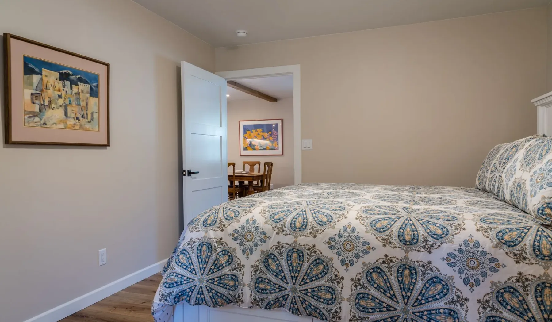 Un dormitorio con una colcha estampada y una puerta abierta.