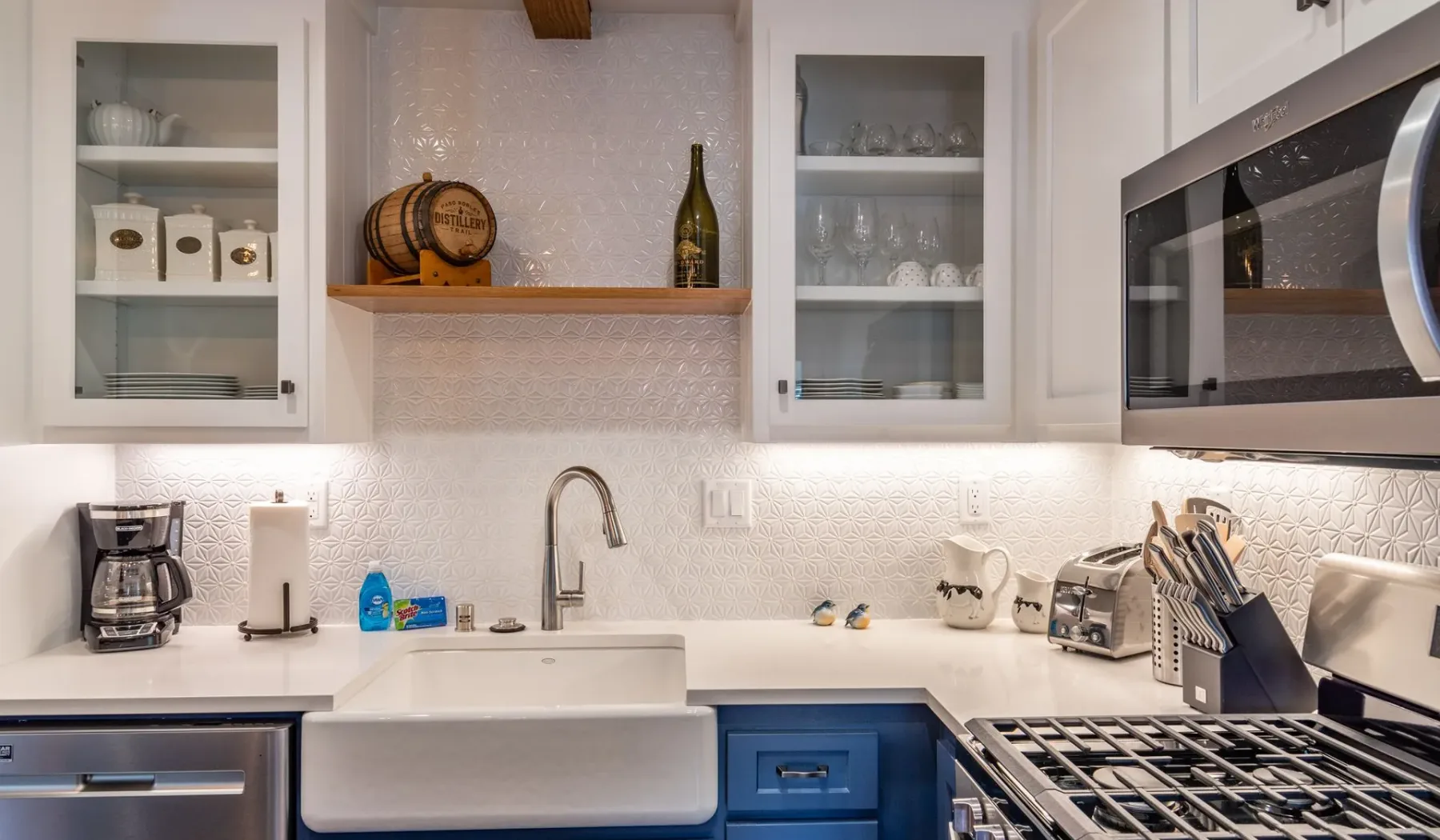 Una cocina luminosa con gabinetes blancos, un fregadero de estilo granja y una estufa.