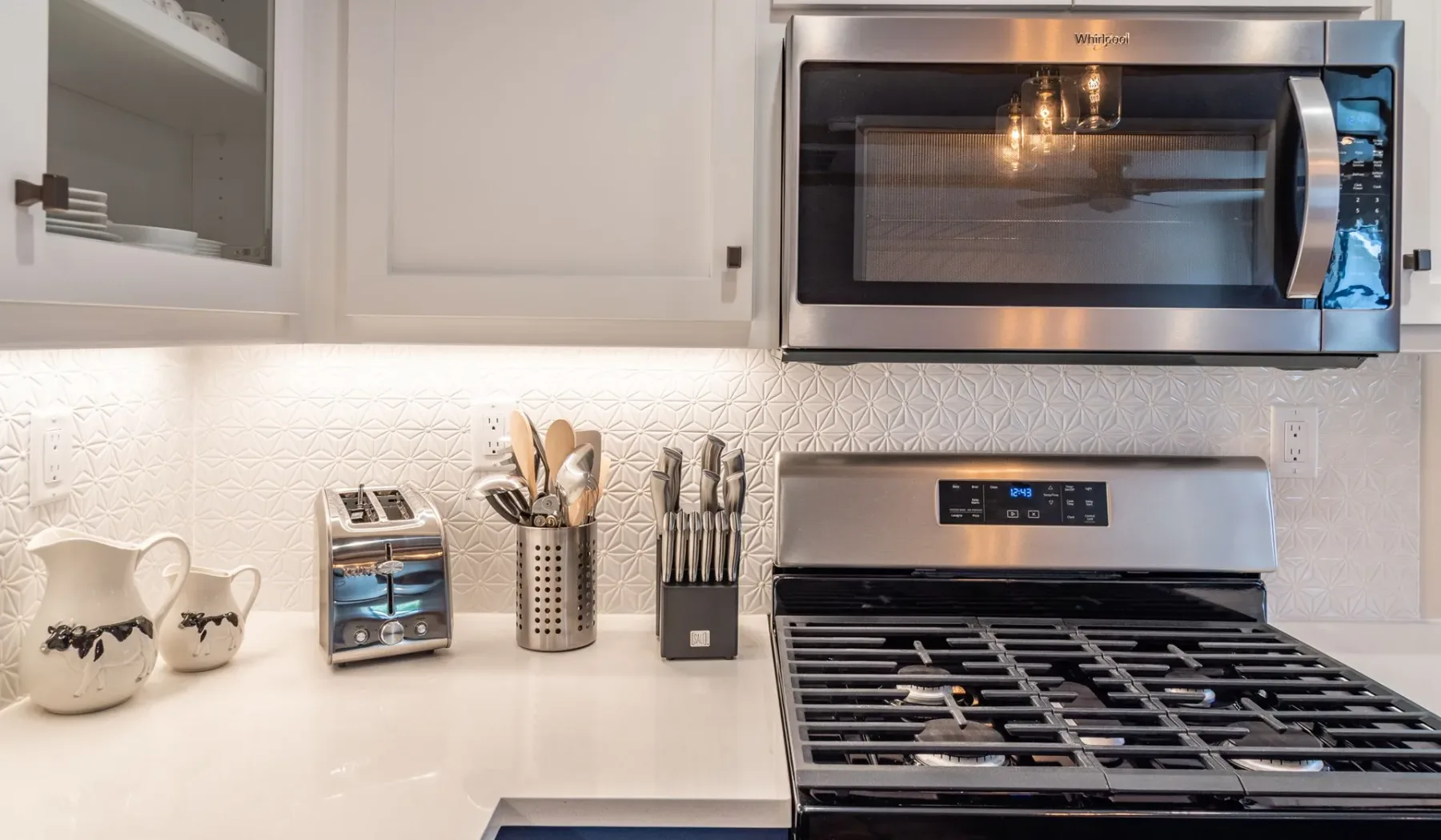 Una cocina luminosa con estufa de gas, microondas y electrodomésticos sobre la encimera.