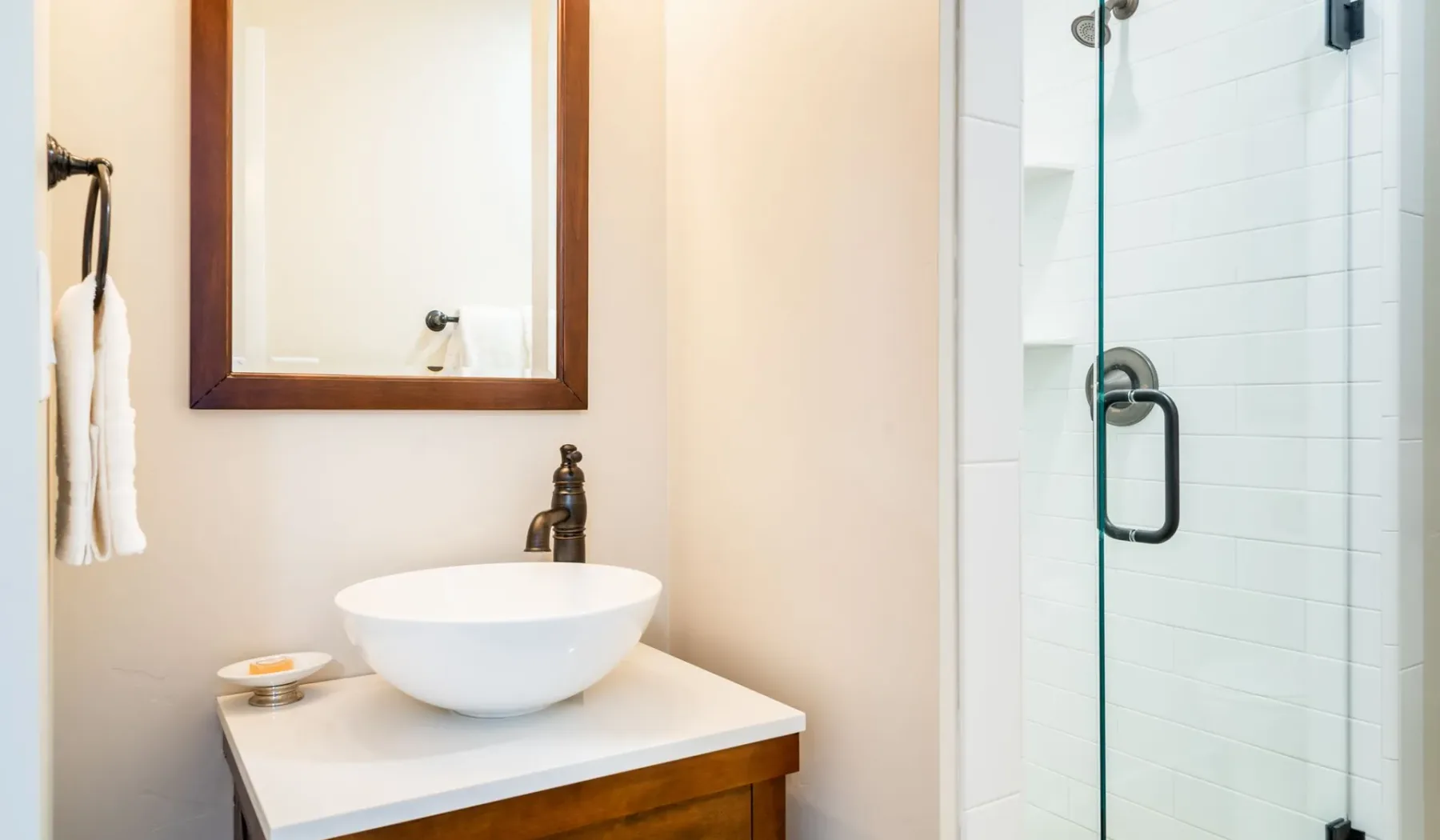 Un lavabo de baño con una cubeta sobre encimera está junto a una ducha de vidrio.