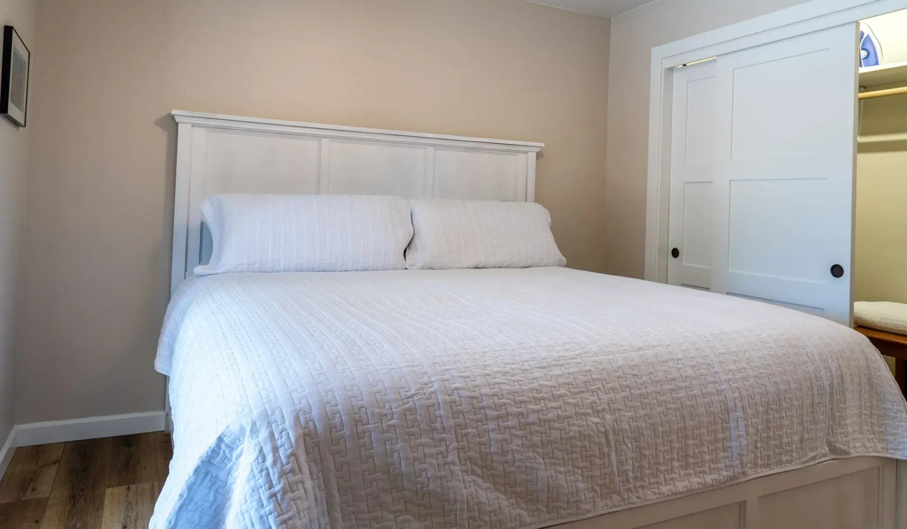 Un dormitorio con una cama bien tendida y ropa de cama blanca.