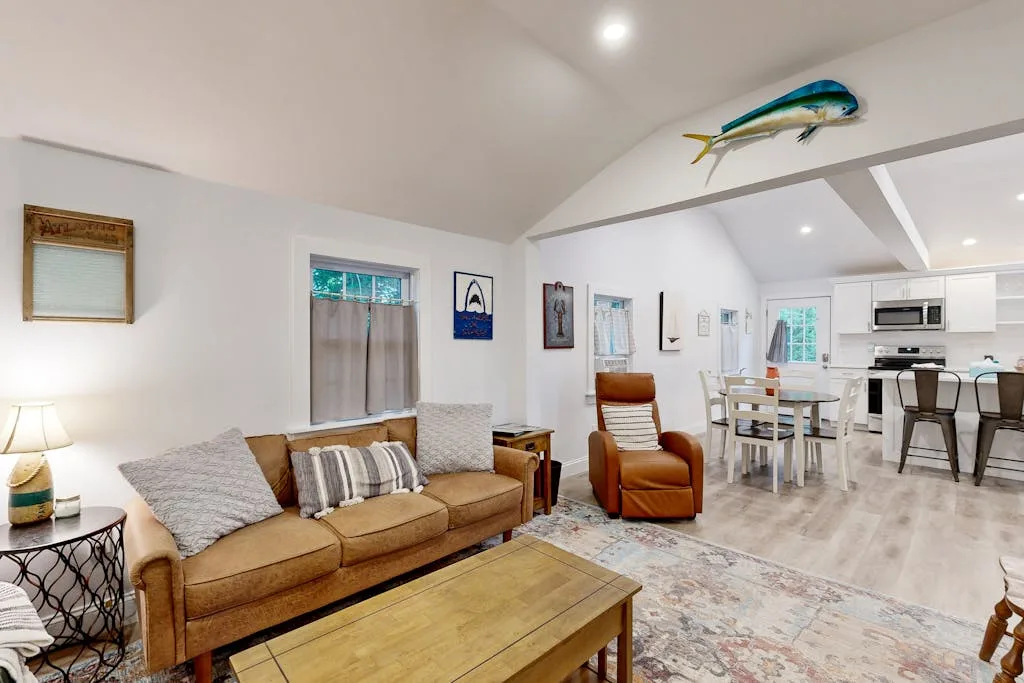 A living room with seating and a coffee table opens onto a dining area and kitchen.