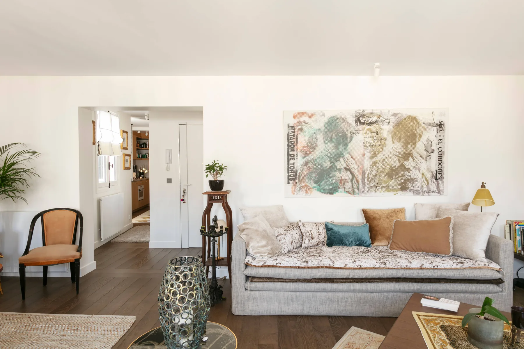 A bright living room with a sofa beneath a large abstract artwork.