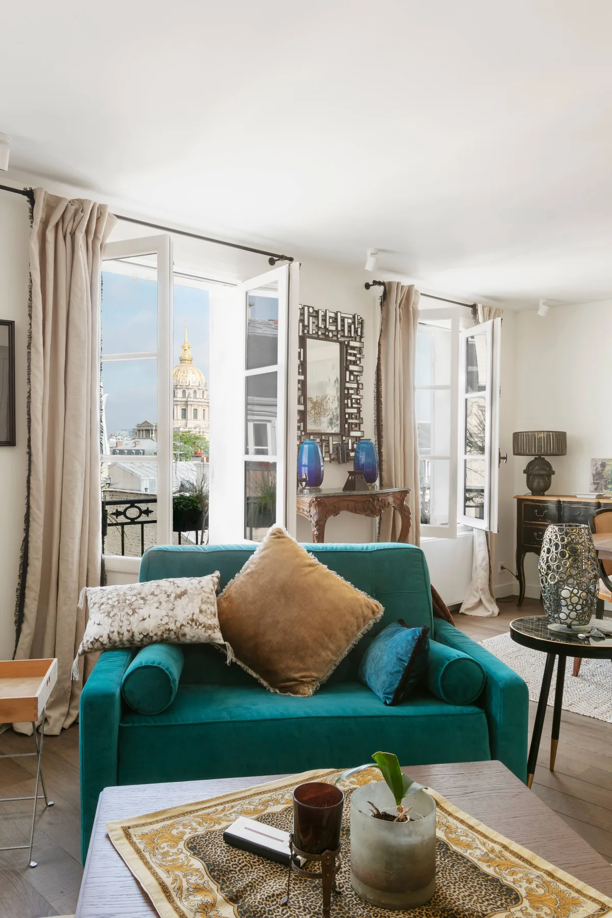 Una sala luminosa con asientos color turquesa, ventanas abiertas y una mesa de centro.