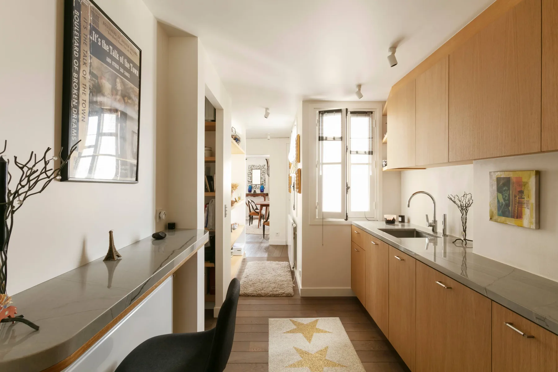 A bright kitchen with wooden cabinets, a long counter, and windows at the far end.