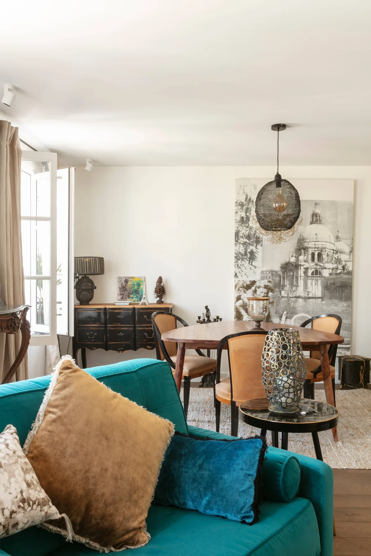 A living and dining room with teal seating and a wooden dining table.