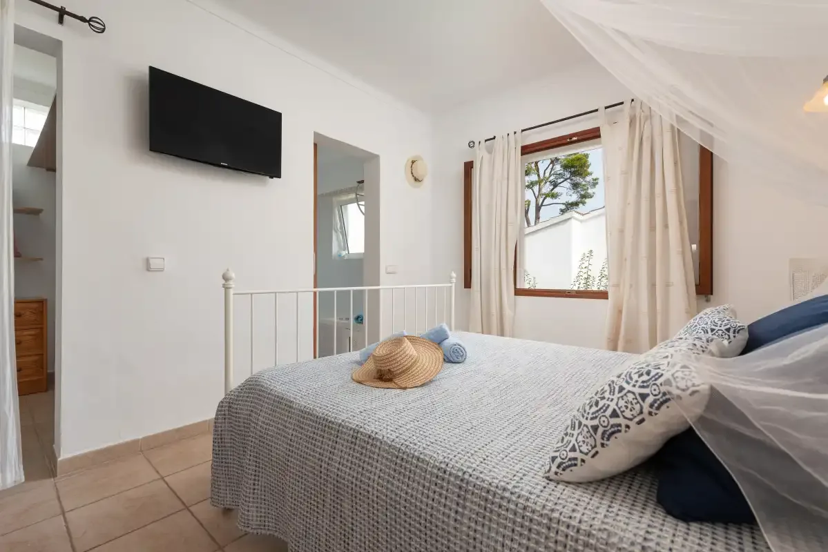 A bedroom with a bed, patterned bedding, and a wall-mounted television.