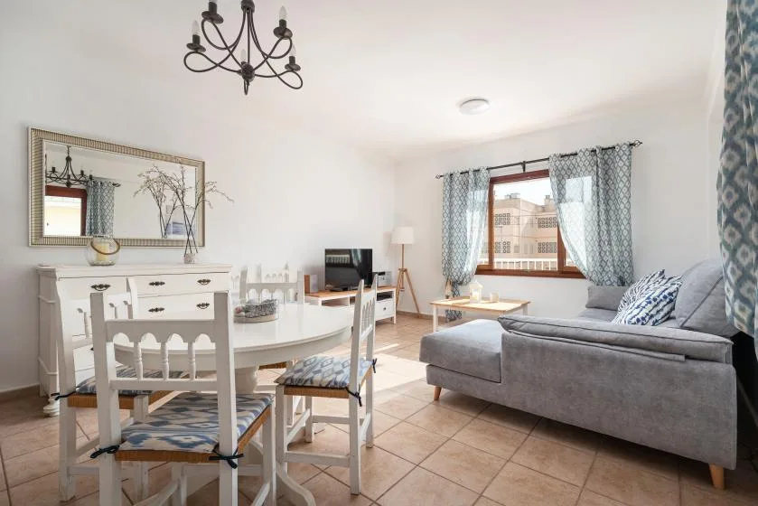 A bright living room with a dining table and gray seating beside the window.
