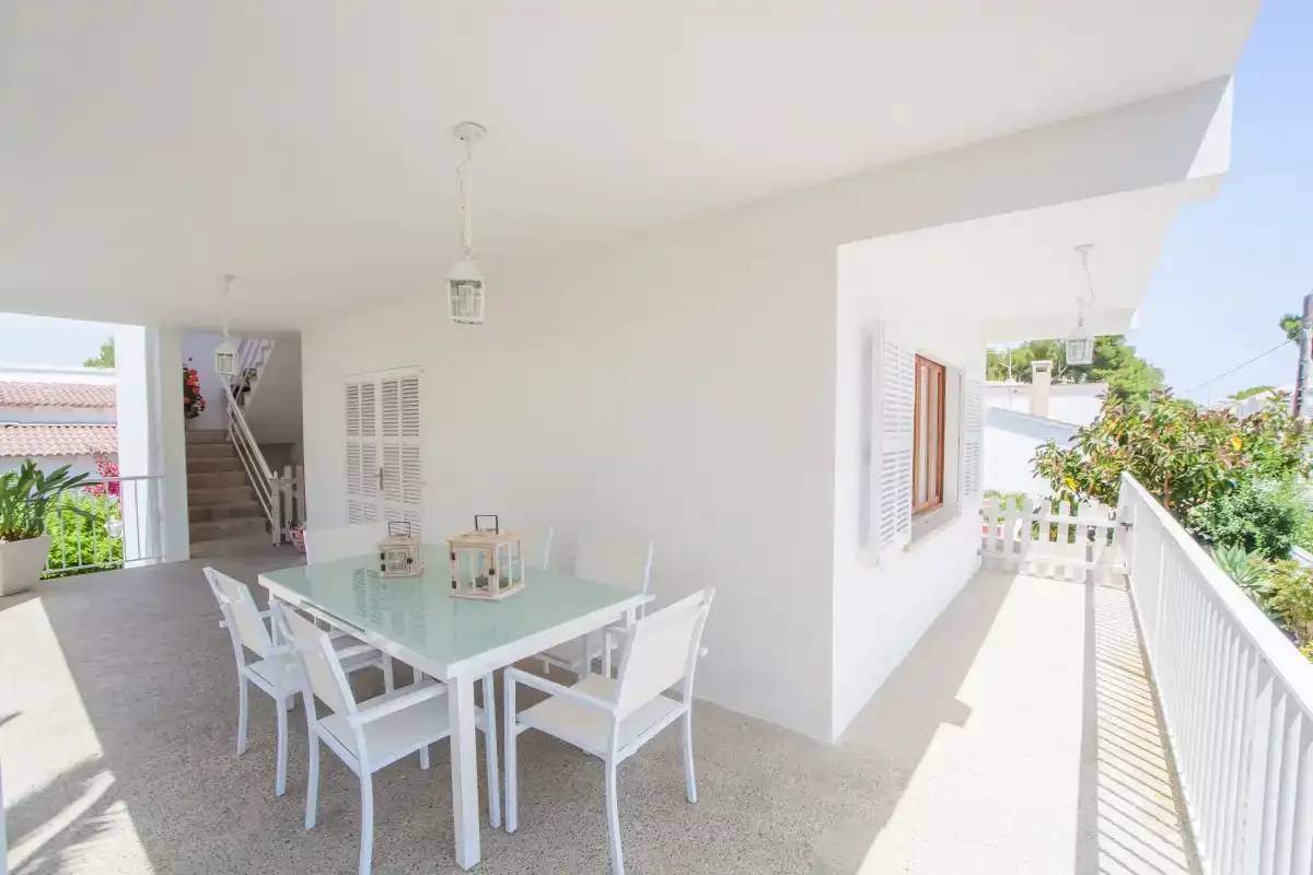 A bright dining area opens onto a balcony with white railings.
