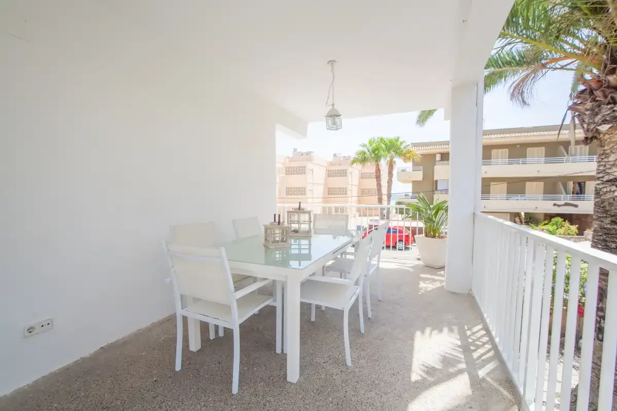 A covered outdoor dining area with a white table and seating.