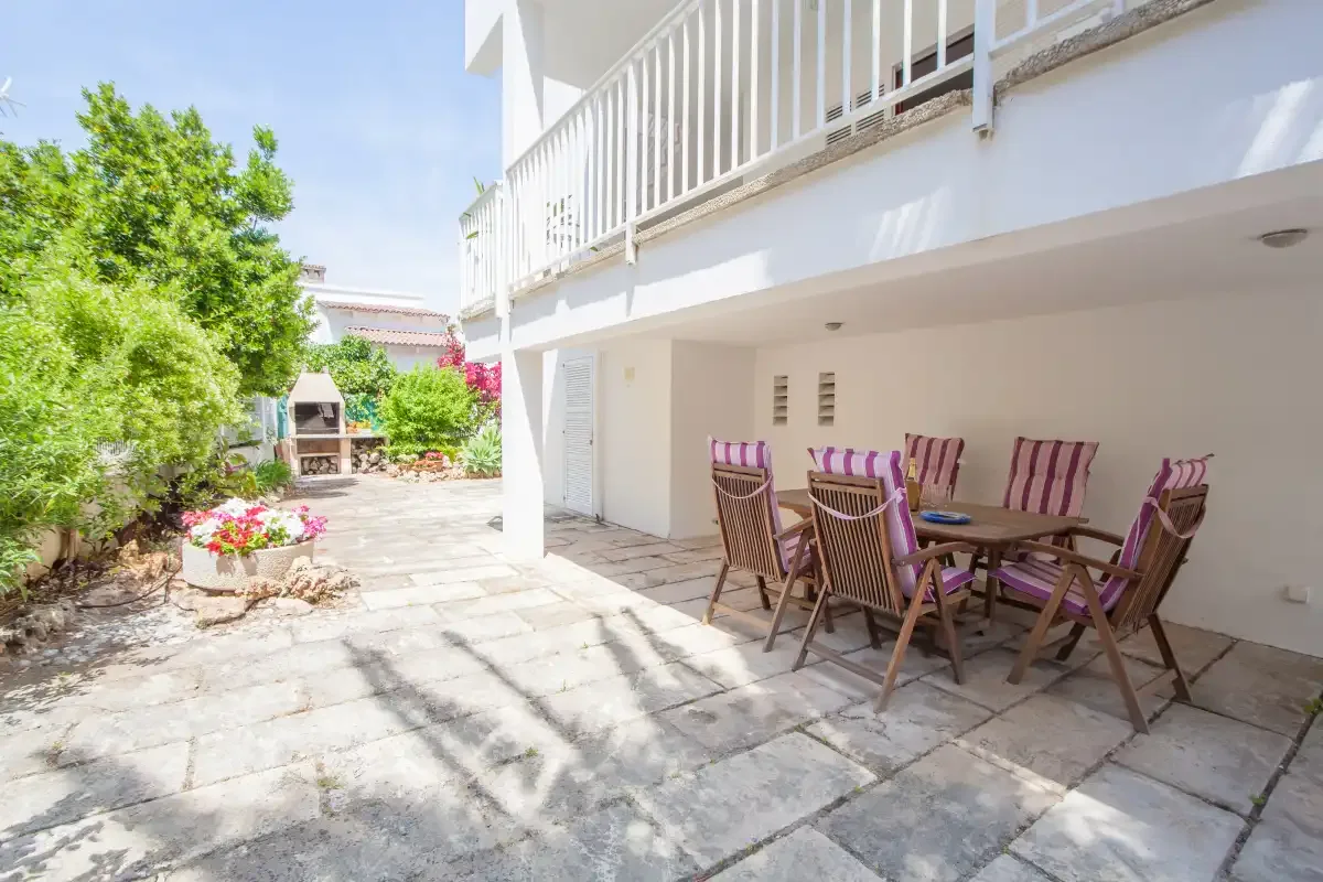A shaded patio with outdoor seating beside a white building.