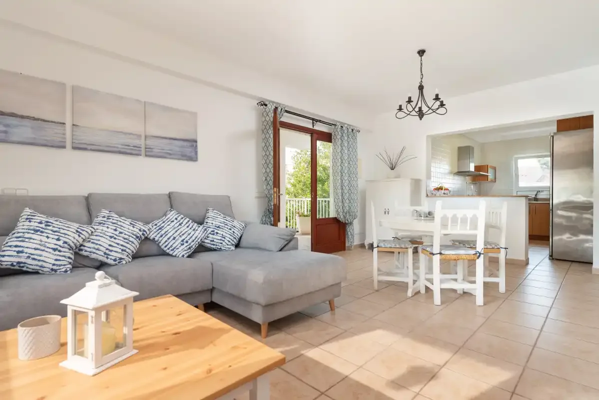 An open-plan living and dining area with a gray seating area and a white dining table.