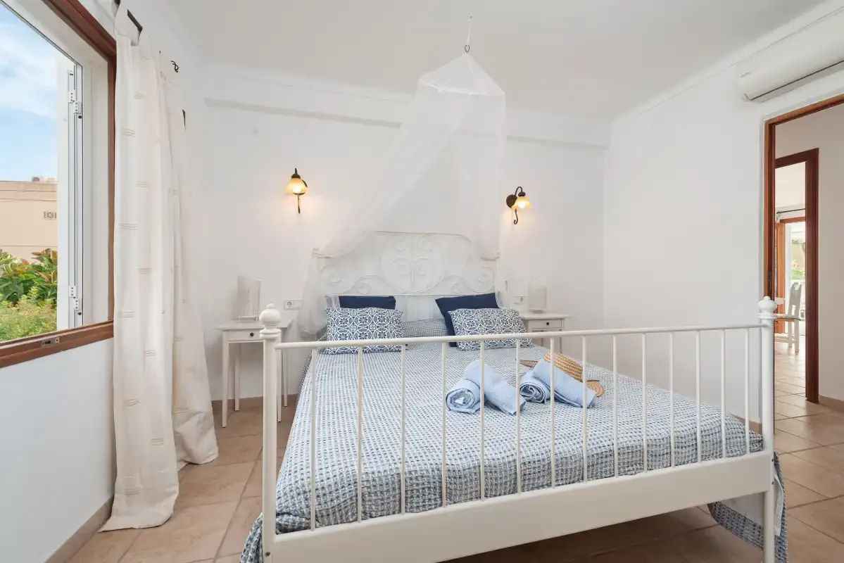 A bright bedroom with a white bed and windows on either side.