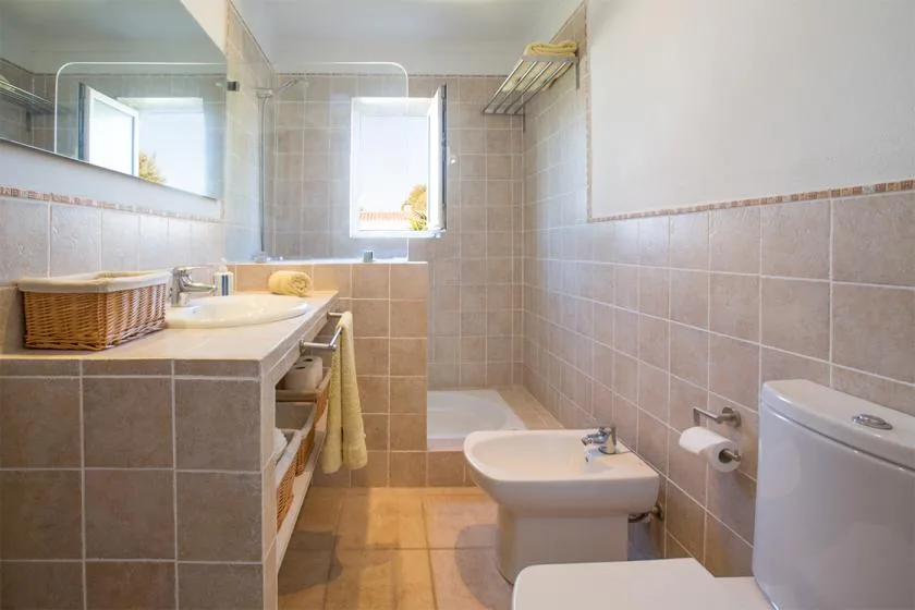 A tiled bathroom with a sink, bidet, and toilet.